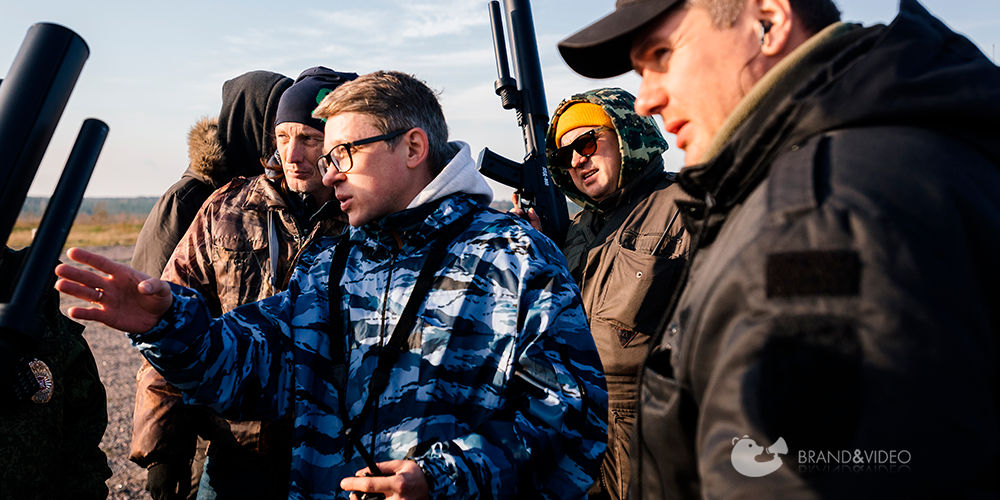 Группа людей обсуждает съемку, военные