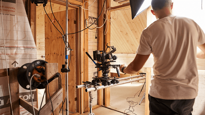 Парень в белой футболке с кинокамерой