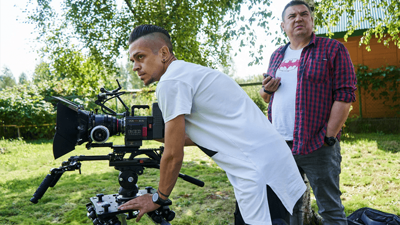 Оператор с кинокамерой в белой футболке