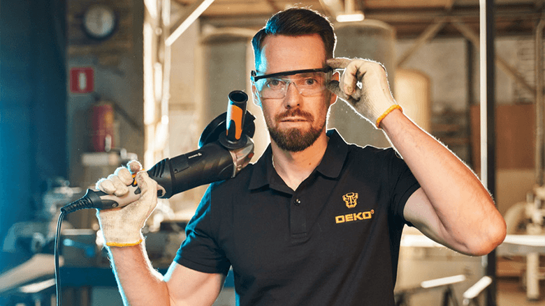 Мужчина в футболке и защитных очках с болгаркой