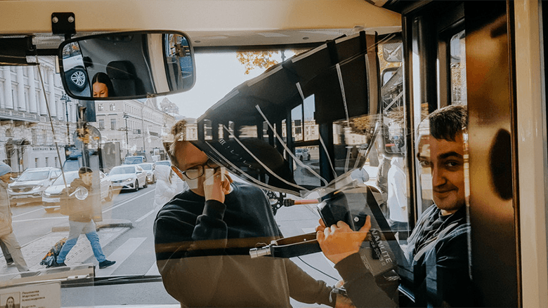 Два молодых человека в кабине автобуса снимают видео