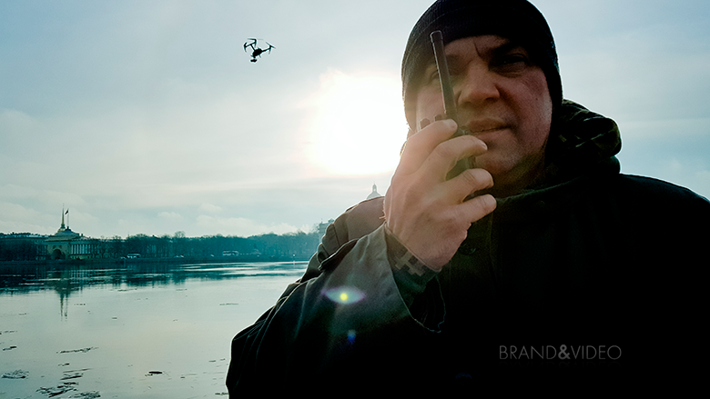 Мужчина с рацией, на заднем плане квадрокоптер